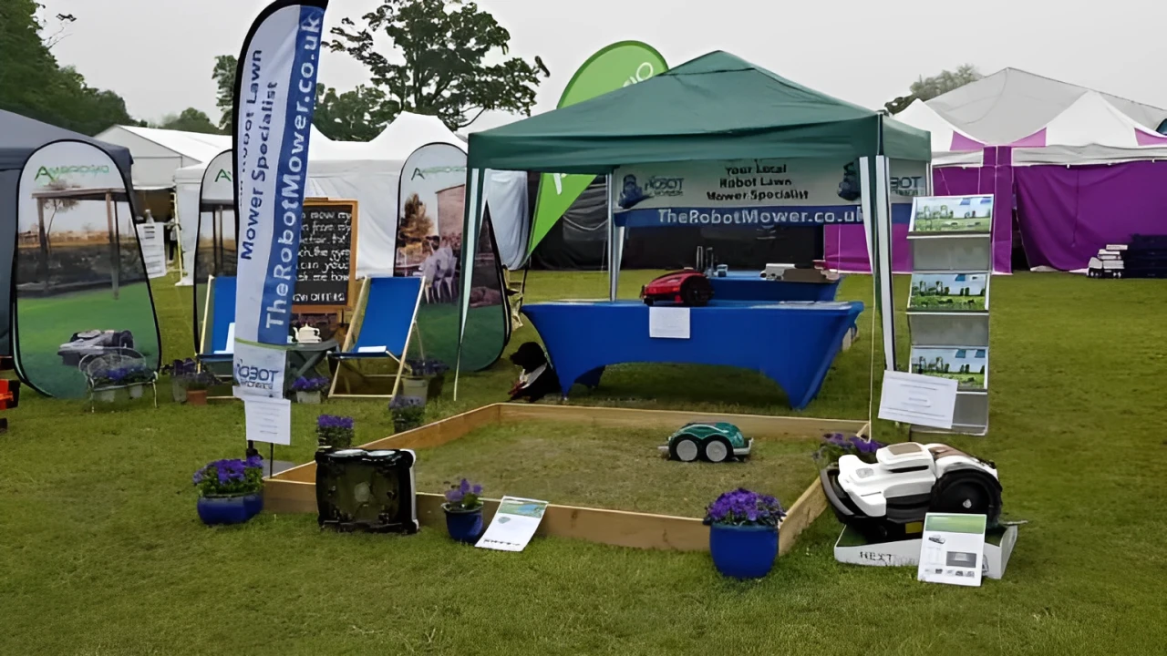 Outdoor exhibition booth with robotic mowers, banners, and a demo grass patch.